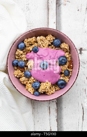 Müsli mit Blaubeeren und Heidelbeere Joghurt in Schüssel auf weißem Holz Stockfoto