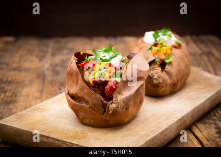 Süßkartoffel kumpir mit Chili con Carne, saure Sahne und Koriander Stockfoto