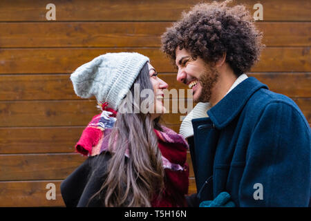 Glückliches junges Paar in winterwear vor der hölzernen Wand Stockfoto