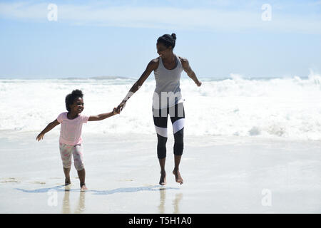 Glückliche Mutter und Tochter, die Spaß am Strand Stockfoto