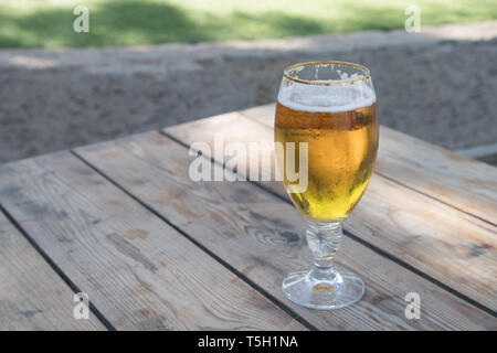 Blick auf kaltes Bier auf hölzernen Tisch in einem klaren Tag Stockfoto