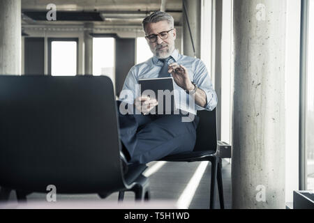 Reifen Geschäftsmann sitzen auf Stuhl mit Tablet Stockfoto