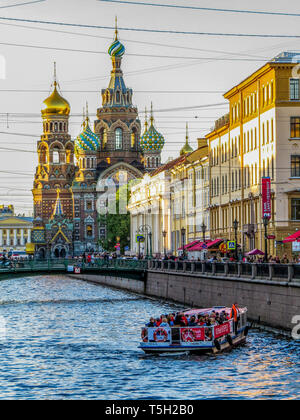 Boot mit Touristen auf Exkursion auf dem Griboyedov Canal mit dem Wahrzeichen Kirche des Erlösers auf Blut vergossen. St. Petersburg, Russland Stockfoto