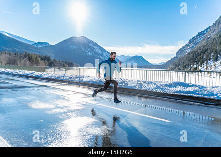 Deutschland, Bayern, sportlichen Mann laufen auf einer Straße im Winter Stockfoto