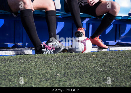 Beine von zwei Fußball-Spieler sitzt auf der Bank am Fußball Feld Stockfoto