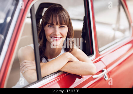 Sorglos Frau in vintage Auto sitzen, lächeln Stockfoto