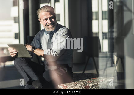 Lächelnd reife Geschäftsmann mit Tablet-PC im Büro Stockfoto