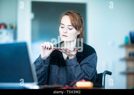Porträt der jungen Techniker im Rollstuhl Kontrolle Material Stockfoto