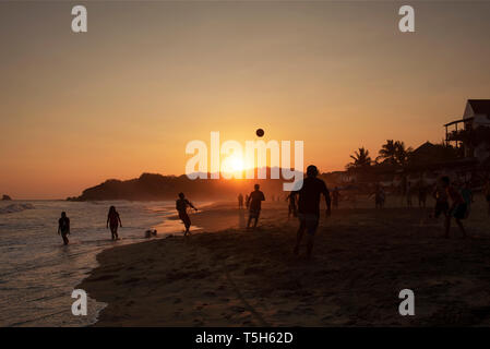 Silhouette von lokalen Männer Fußball spielen auf dem sandigen Strand von Zipolite. Oaxaca, Mexiko. Apr 2019 Stockfoto