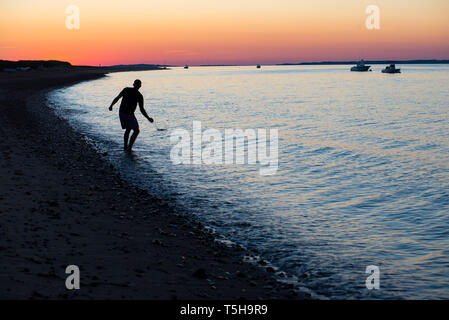 Der Mensch überspringen Steine am Strand bei Sonnenuntergang, Cape Cod Stockfoto