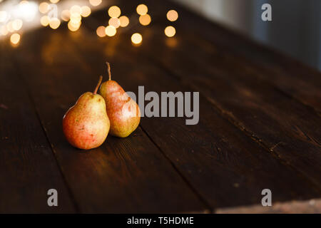 Schöne reife leckere Birnen auf einem großen Küche Holztisch mit einer Girlande der Lichter. Ein schöner Bildschirmschoner für einen Artikel über eine gesunde Ernährung, eine c Stockfoto