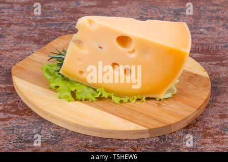 Maasdamer Käse auf dem Bord serviert Salatblättern und Rosmarin Stockfoto