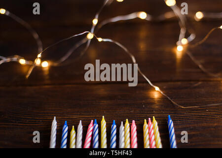 Girlande Lichter und Kerzen für den Kuchen auf einem dunklen Hintergrund. Gute Screensaver für Geburtstagsgrüße, Konzept der Grußkarte, Jubiläum Stockfoto