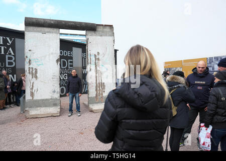 Berlin, Deutschland - Touristen posieren für Fotos neben einem Abschnitt der Berliner Mauer in der Nähe von Checkpoint Charlie Stockfoto