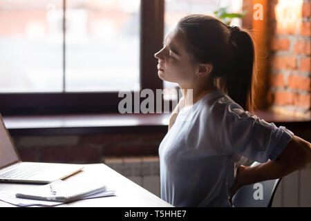 Frauen sitzen am Tisch sitzende Tätigkeiten Rückenschmerzen fühlt Stockfoto