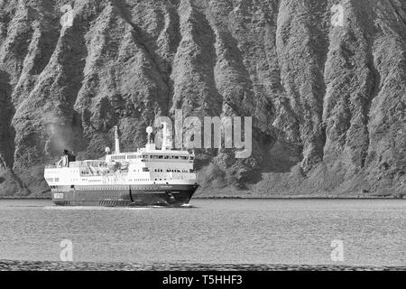 Schwarz-weiß-Foto der Hurtigruten-Fähre, MS Vesterålen nähert sich der norwegischen Fischerstadt Honningsvåg, den Seiten des Fjords Zwerg des Schiffes Stockfoto