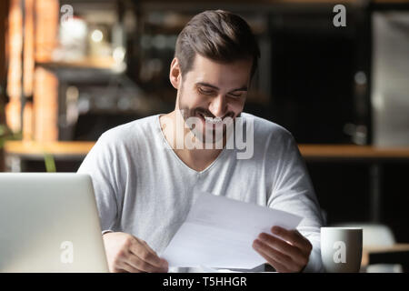 Tausendjährige Geschäftsmann Lesen gedruckter Brief mit guten Nachrichten Zufrieden Stockfoto