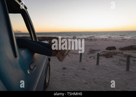 Frau entspannend mit Fuß oben in ein Auto am Strand Stockfoto