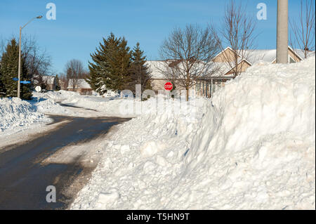 Schnee gepflügt hoch durch die Straße der Stadt. Stockfoto