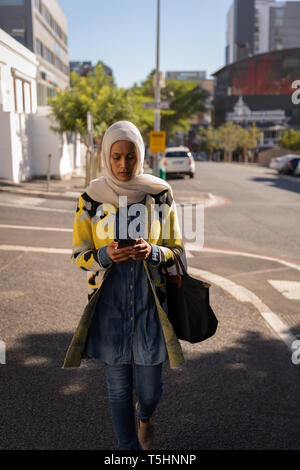 Frau mit Handy beim Gehen auf der Straße Stockfoto