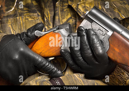 Hände von Hunter in der Tarnung laden die doppelläufige Schrotflinte, Nahaufnahme Stockfoto