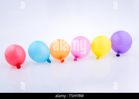 Bunte kleine Luftballons in Linie auf weißem Hintergrund Stockfoto