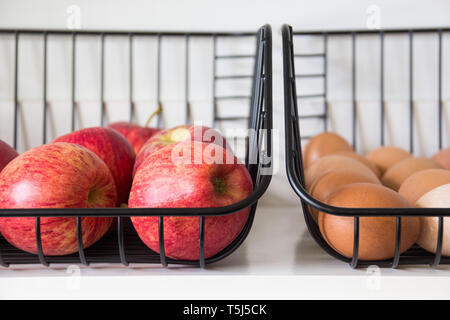 Äpfel und Eier in Körben auf einem Regal Stockfoto