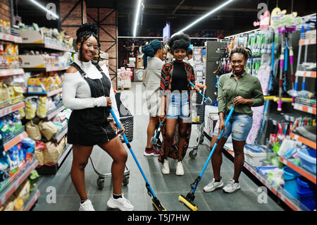 Gruppe von fünf afrikanischen womans mit Staub Mop, WC-Bürste und Schaufel Spaß im Haushalt Reinigung Produkte Abteilung im Supermarkt. Stockfoto