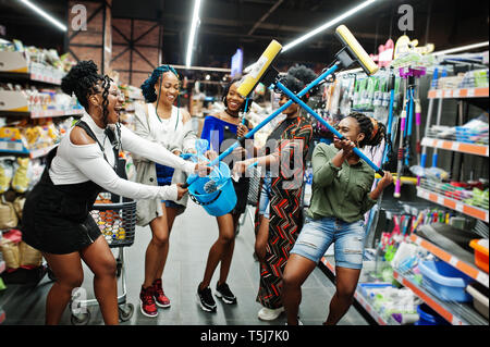 Gruppe von fünf afrikanischen womans mit Staub Mop, WC-Bürste und Schaufel Spaß im Haushalt Reinigung Produkte Abteilung im Supermarkt. Stockfoto