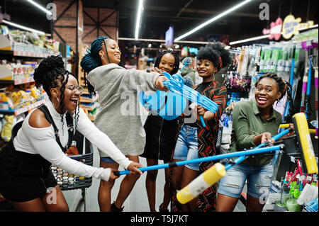 Gruppe von fünf afrikanischen womans mit Staub Mop, WC-Bürste und Schaufel Spaß im Haushalt Reinigung Produkte Abteilung im Supermarkt. Stockfoto