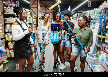 Gruppe von fünf afrikanischen womans mit Staub Mop, WC-Bürste und Schaufel Spaß im Haushalt Reinigung Produkte Abteilung im Supermarkt. Stockfoto