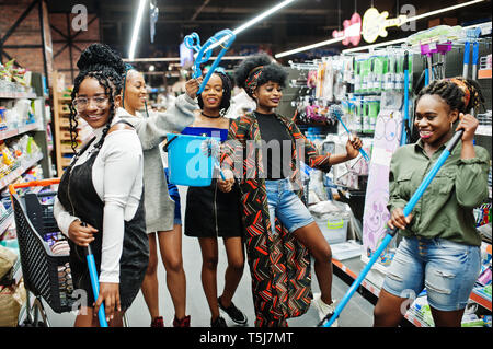 Gruppe von fünf afrikanischen womans mit Staub Mop, WC-Bürste und Schaufel Spaß im Haushalt Reinigung Produkte Abteilung im Supermarkt. Stockfoto