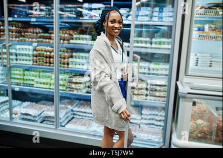 Afrikanische amerikanische Frau in der Nähe von Kühlschrank Regal verkauft Milchprodukte Ei Karton im Supermarkt. Stockfoto