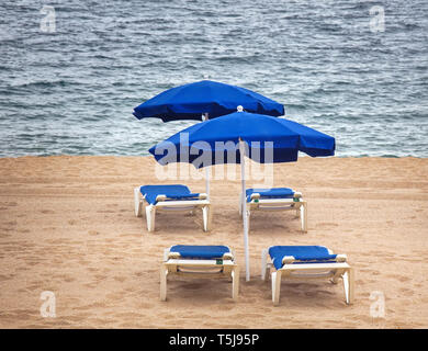 Sonnenliegen und Sonnenschirm am Meer Sandstrand auf dem Hintergrund des Meeres. Warten auf Urlauber in den Badeort Stockfoto