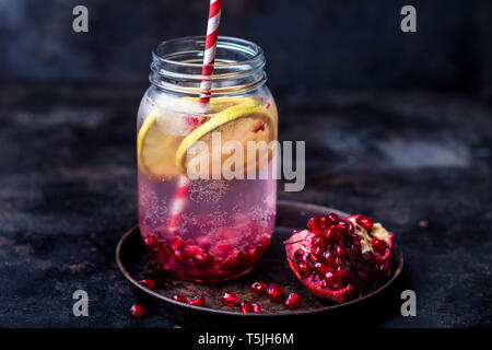 Obst infundiert Wasser mit Zitronenscheiben, gemahlen Granatapfel Samen und Mineralwasser Stockfoto
