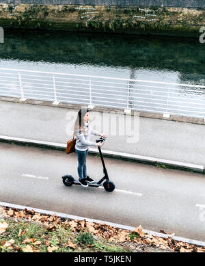 Junge Frau, Elektrische Roller auf der Straße Stockfoto