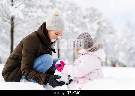 Glückliche Mutter spielt mit Tochter im Winter Landschaft Stockfoto