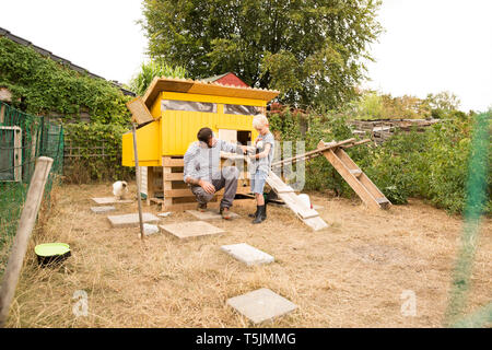 Vater und Sohn mit polnischen Hühner an chickenhouse im Garten Stockfoto