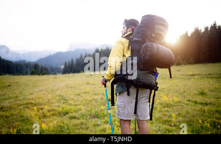 Attraktive Wanderer mit großen Reisen Rucksack oben auf dem Berg Trail und lächelnd Stockfoto