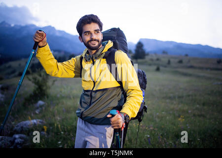 Attraktive Wanderer mit großen Reisen Rucksack oben auf dem Berg Trail und lächelnd Stockfoto