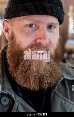 Portrait von lächelnden bärtiger Mann mit hellbraunem Haar, trug schwarze Mütze. Stockfoto
