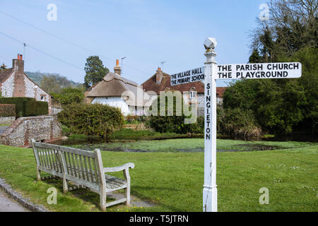 Leeren Bank und Wegweiser auf einem Dorf auf dem Land Grün durch Teich in South Downs National Park. Singleton, Chichester, West Sussex, England, Großbritannien, Großbritannien Stockfoto