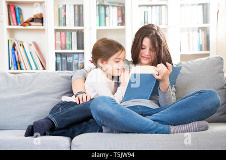 Schwestern sitzen auf der Couch, Buch lesen Stockfoto