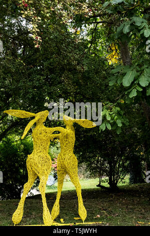 Zwei boxen Hasen auf die Hinterbeine, ein großer Garten Skulptur in Gelb gestrichen. Stockfoto