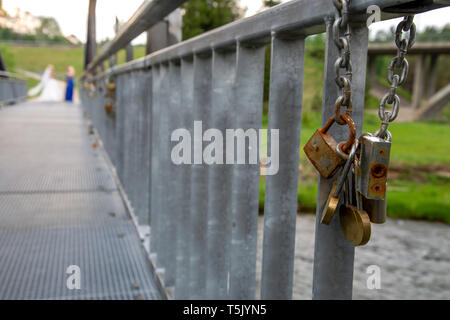 Unterschiedlichen Alters Vorhängeschlösser auf dem Metall Brücke in Lettland. Hochzeit Tradition. Rostige Schlösser auf der Brücke hängenden Kette. Stockfoto