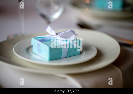 Festliche Tischdekoration mit handgefertigten Geschenkbox an der Platte. Hellblau handgefertigten Geschenkbox in der Platte auf Hochzeit Tisch. Stockfoto