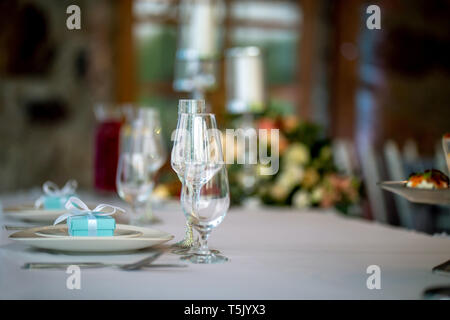 Festliche Tischdekoration mit verzierten Gläsern und handgearbeitete Geschenkboxen. Handgefertigte Geschenk Box im Teller und Gläser auf Hochzeit Tisch. Stockfoto