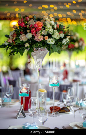 Hochzeit Tischdekoration. Schönen Blumenstrauß in der Vase auf dem Tisch, neben Tellern, Gläsern und Geschenkboxen. Blumenstrauß, Gläser, gif Stockfoto