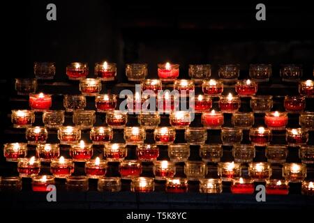 Rote Kerzen in Gläsern leuchtet in einer dunklen Kirche Stockfoto