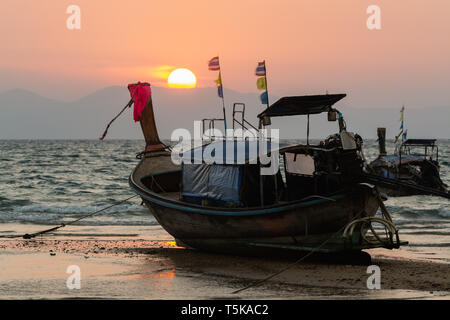 Long Tail hölzerne Boote am Klong Muang Beach bei Sonnenuntergang in der Provinz Krabi, Thailand. Stockfoto